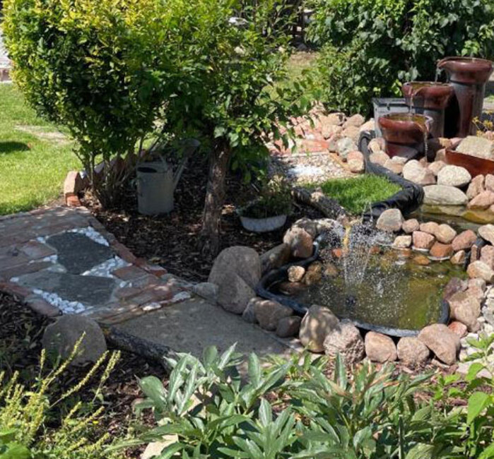 Blick auf einen Barfußpfad mit Springbrunnen im Grünen.